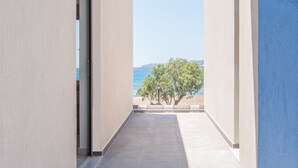A corridor with a view of the sea and a tree.