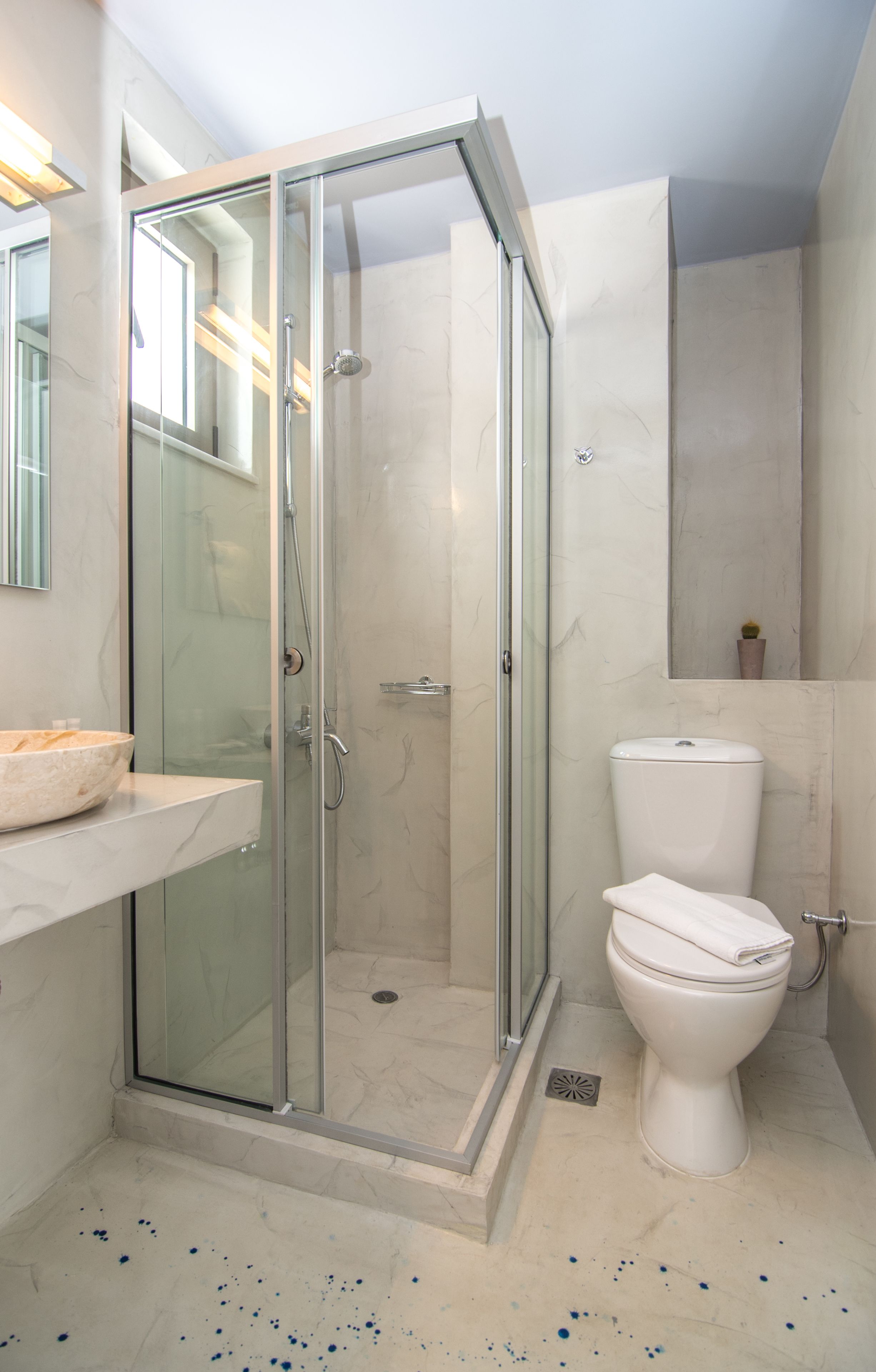 A modern bathroom with a glass-enclosed shower, a white toilet, and a marble-tiled floor.