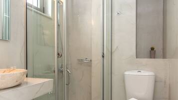 A modern bathroom with a glass-enclosed shower, a white toilet, and a marble-tiled floor.