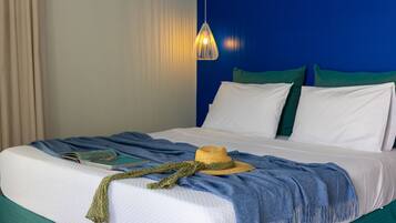 A neatly made bed with a hat, a book, and a blanket.