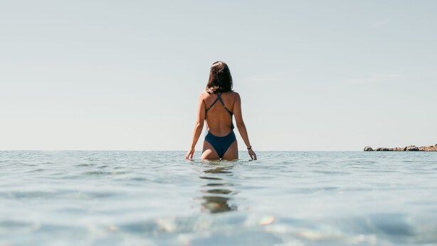 A person walking in shallow water towards the horizon.