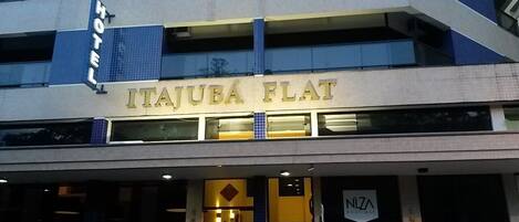 The exterior of Itajuba Flat hotel with a visible entrance and a sign for NZA Boutique.
