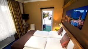 A hotel room with a bed, a TV, a fan, and a painting on the wall. - C&S Hotel (Pinneberg)