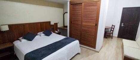 Une chambre d’hôtel comprenant un lit, des tables de chevet, une armoire, un bureau et une chaise.