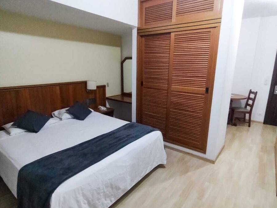 Ett hotellrum med en säng, sängbord, en garderob, ett skrivbord och en stol.