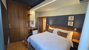 A hotel room with a bed, wooden wardrobe, bedside table, lamp, and artwork on the wall. - Hotel Tenda (Marilia)