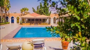 A swimming pool with lounge chairs and a covered seating area. - Monotel Dar El Barka (Nouakchott)