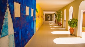 A corridor with a blue mural, potted plants, and arches. - Monotel Dar El Barka (Nouakchott)