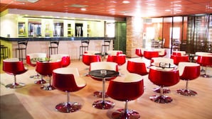 A restaurant with red and white tables and chairs, a bar area, and a stone wall. - Monotel Dar El Barka (Nouakchott)