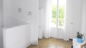 A bright, white room with a large window, a clock on the wall, and a small plant on a table. - La Pergola (Vezzano Ligure)
