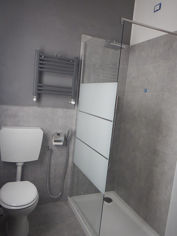 Un baño moderno con inodoro, cabina de ducha y barra para toallas.