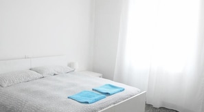 A minimalist bedroom with a bed, white curtains, and a bedside table. - La Pergola (Vezzano Ligure)