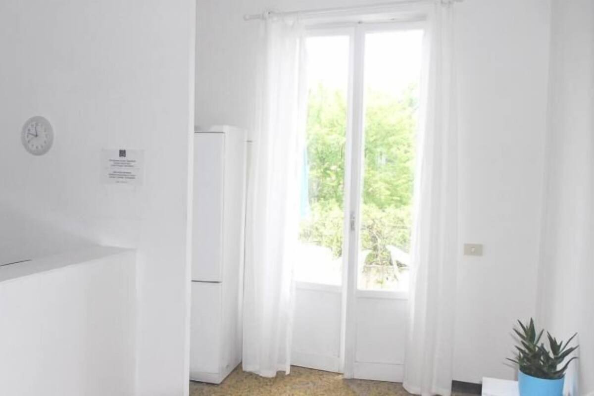 A white room with a window, a clock, and a notice on the wall.