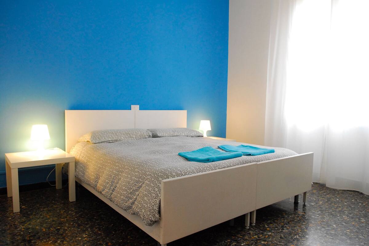 A bedroom with a bed, two bedside tables, and a window with curtains.