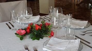 A table set for dining with multiple wine glasses, a centerpiece of red roses, and neatly arranged cutlery.