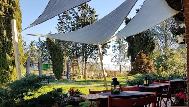 Een terras met tafels en stoelen onder een grote luifel.