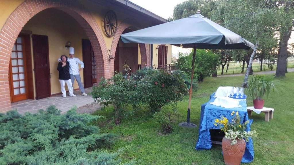 A building with a brick facade, a covered patio area, and a table with a blue tablecloth and flowers.