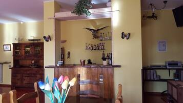 A dining area with a wooden bar, a chandelier, and a butterfly wall decoration.