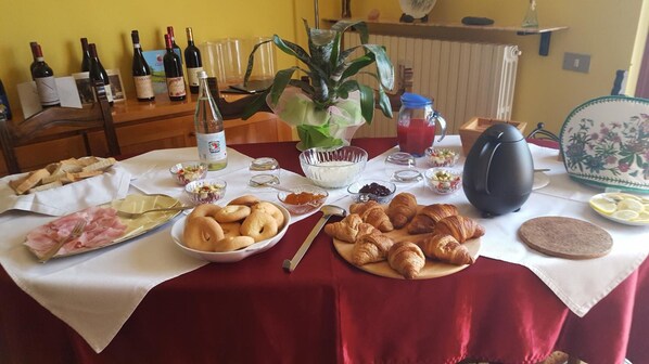 A breakfast table with croissants, ham, and various condiments. - Allevamento B&B (Pozzolgroppo)
