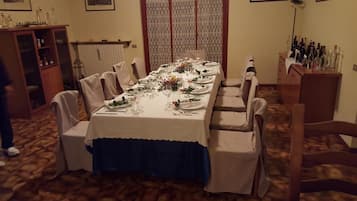 Un comedor con una mesa larga dispuesta para una comida, rodeada de sillas.