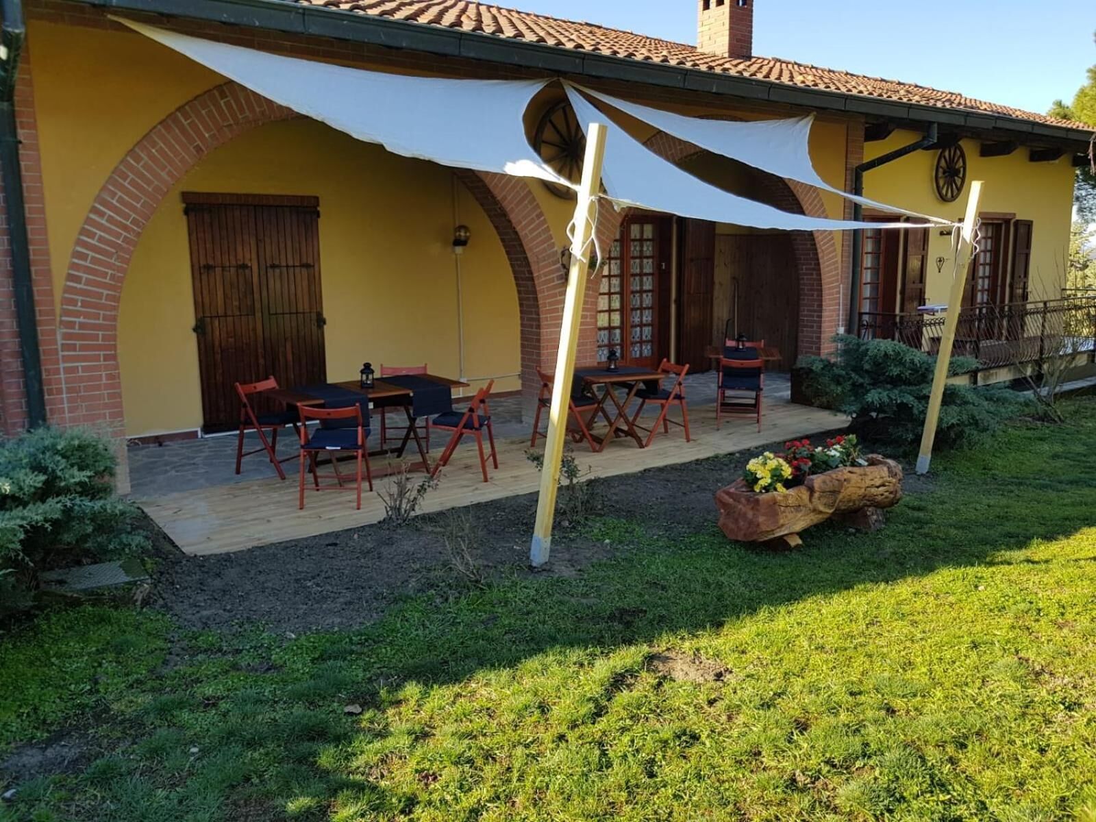Um edifício amarelo com arco de tijolos, área de estar ao ar livre e um jardim.