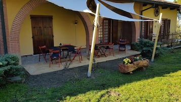 Um edifício amarelo com arco de tijolos, área de estar ao ar livre e um jardim.