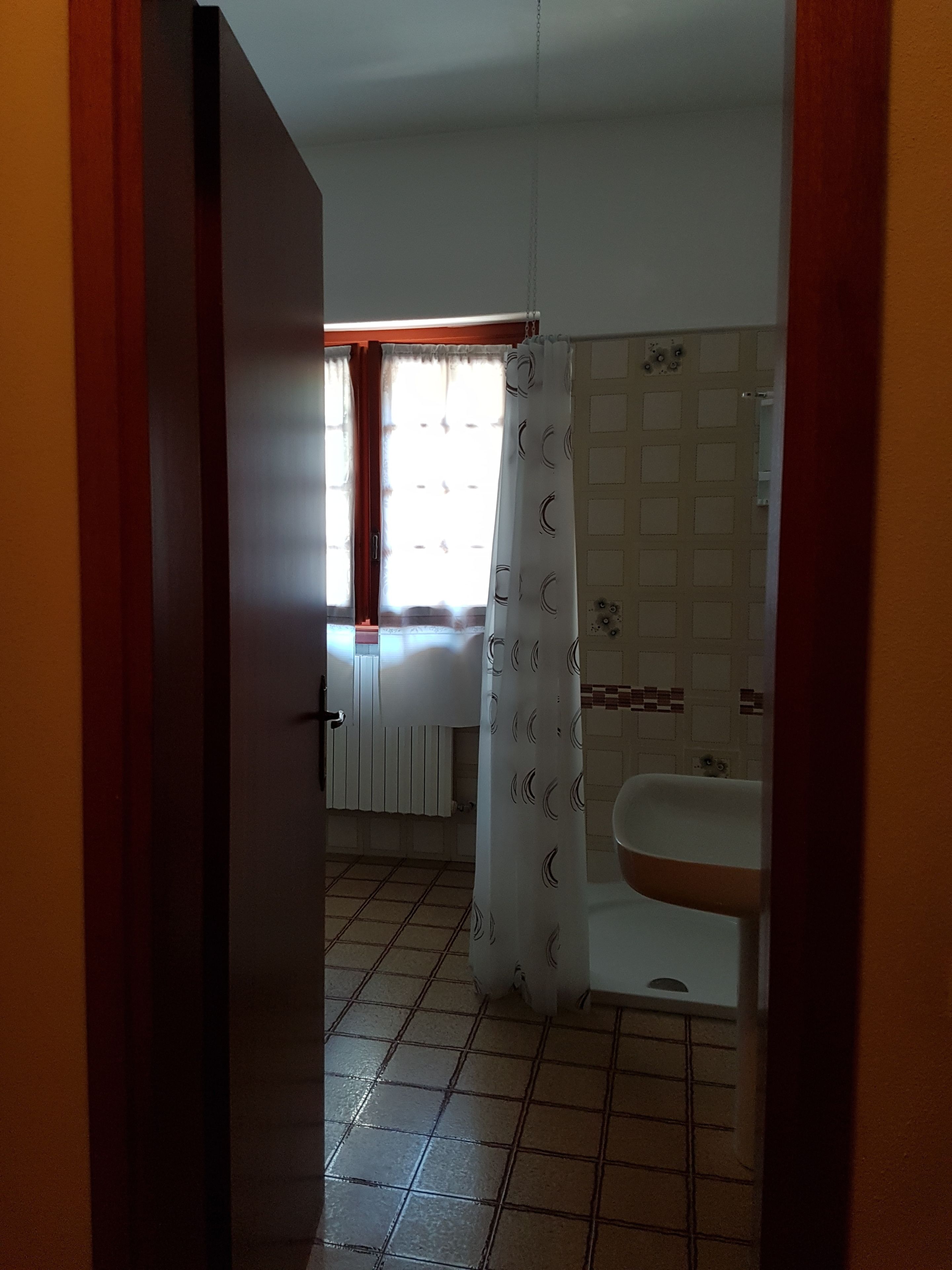 A bathroom with a tiled floor, a sink, and a shower curtain.