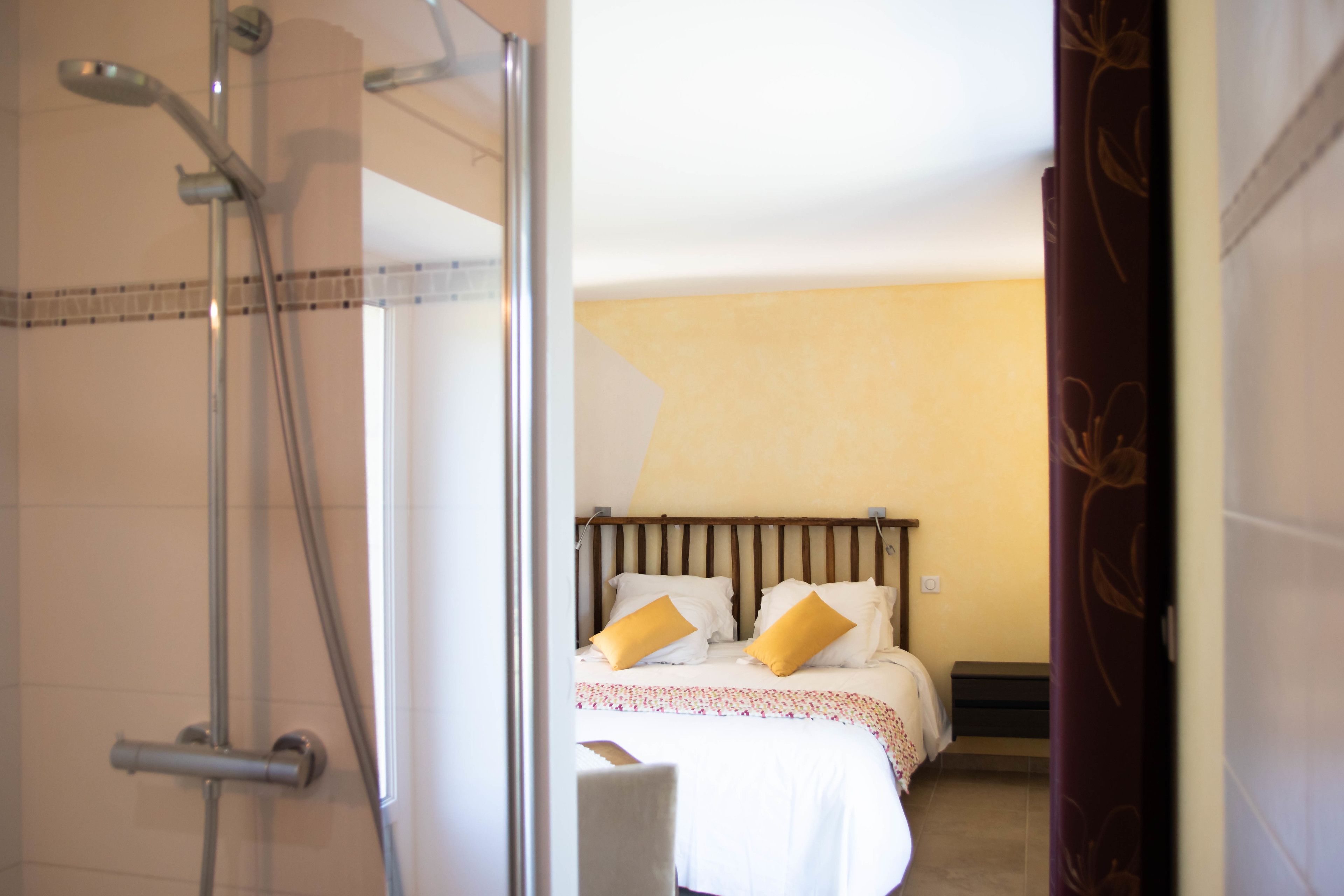 Een hotelkamer met een douche, een bed met twee kussens en een nachtkastje.