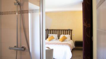 Een hotelkamer met een douche, een bed met twee kussens en een nachtkastje.