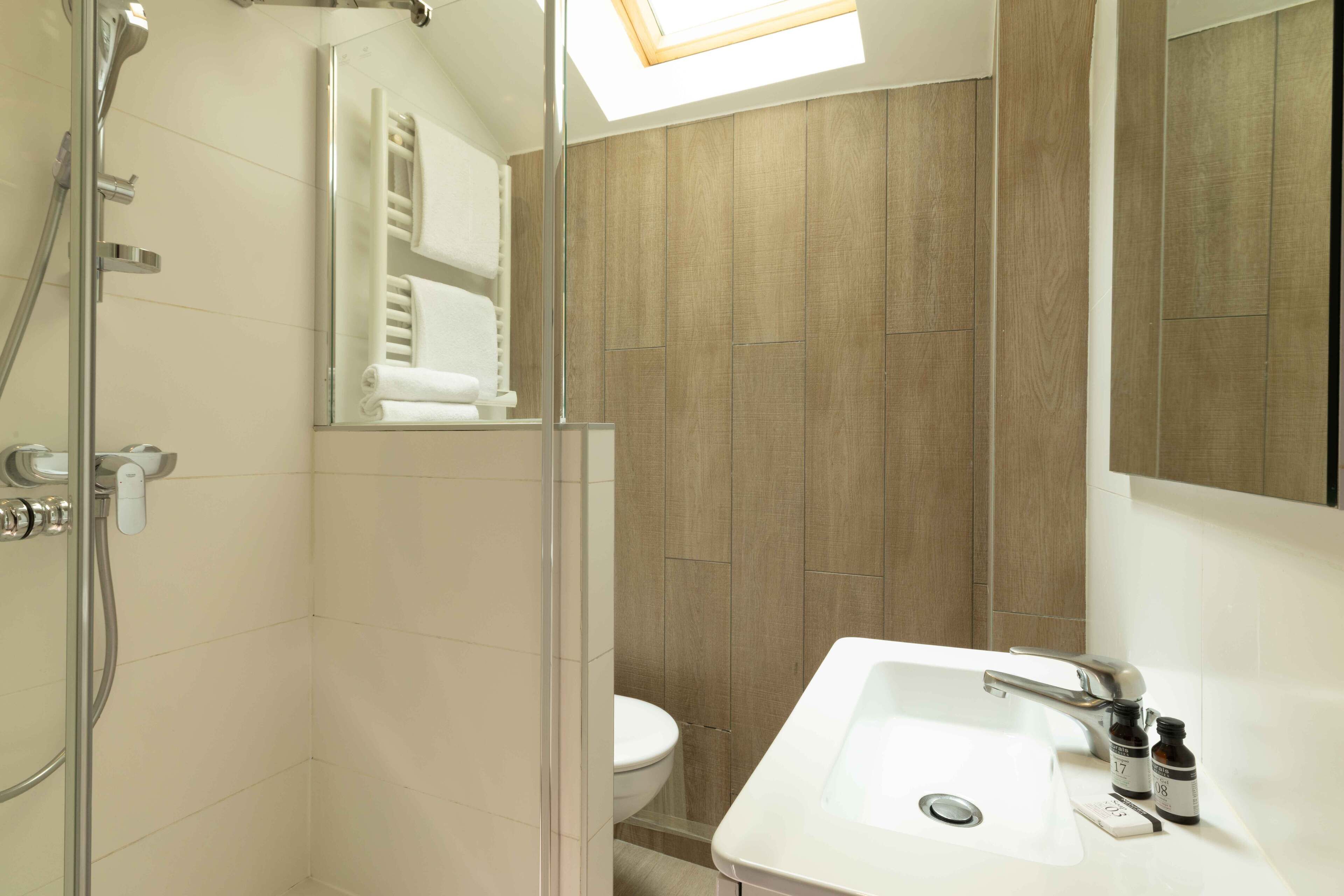 A modern bathroom with a shower, toilet, and sink.