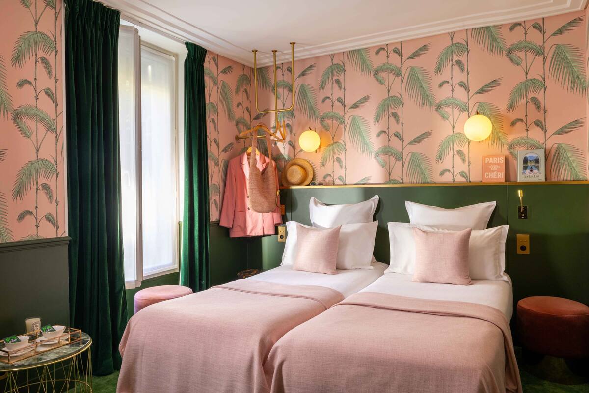 A hotel room with a bed, a vanity with a mirror, a round table with a tray of items, and a window with curtains.