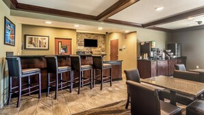 A bar area with stools, a stone wall, and a flat-screen TV. - Cobblestone Inn & Suites - Lakin (Lakin)