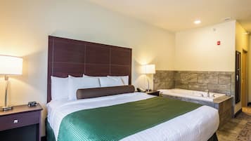 Une chambre d’hôtel avec un grand lit, une table de chevet avec une lampe, une salle de bain avec une baignoire et un mur en marbre.