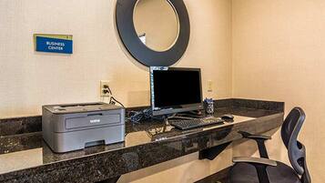 A business center with a desktop computer, printer, and a sign labeled "BUSINESS CENTER".