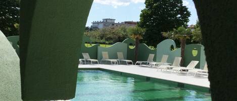 Una piscina con sillas de descanso y vistas a edificios al fondo.