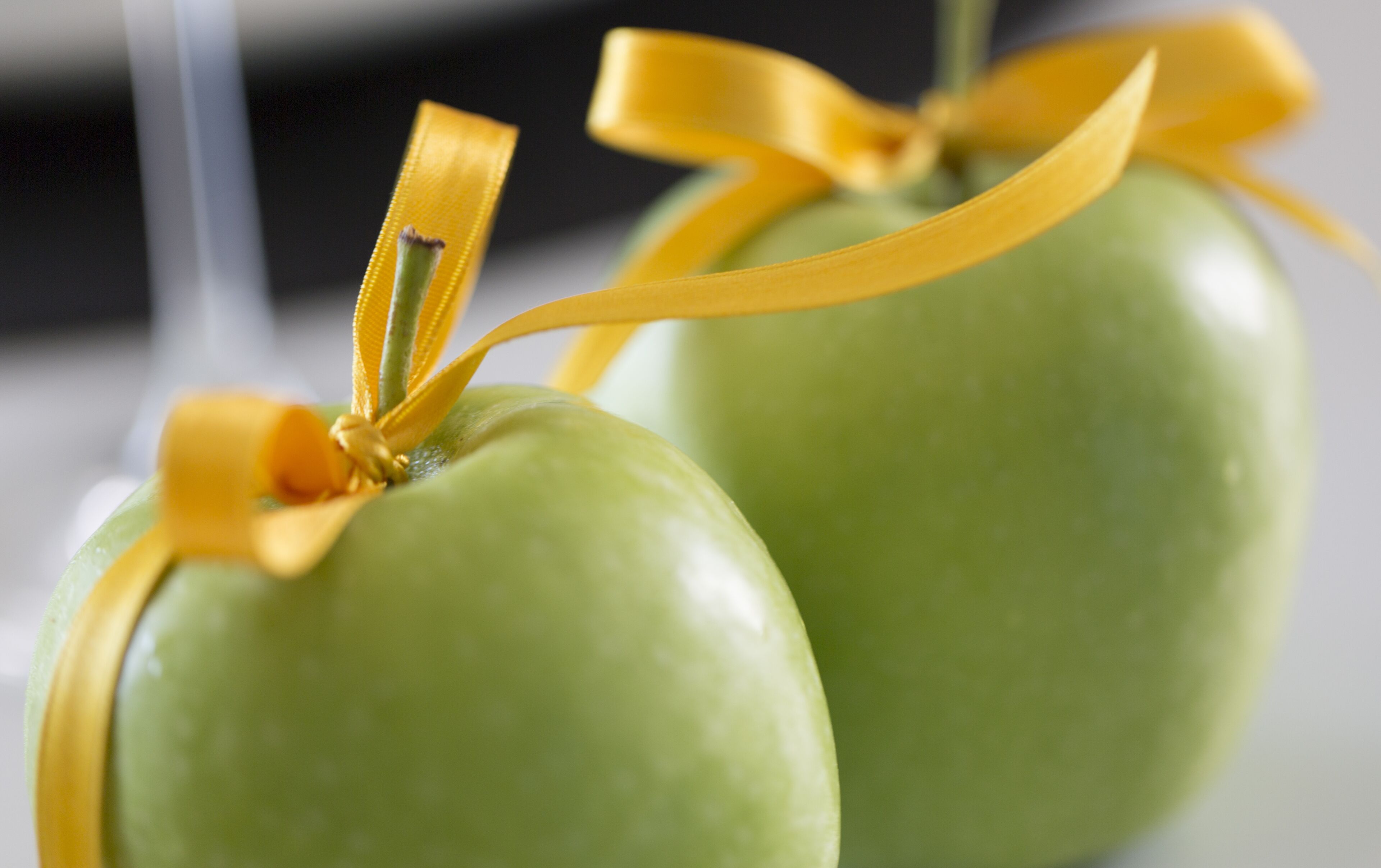 Two green apples tied with yellow ribbons.