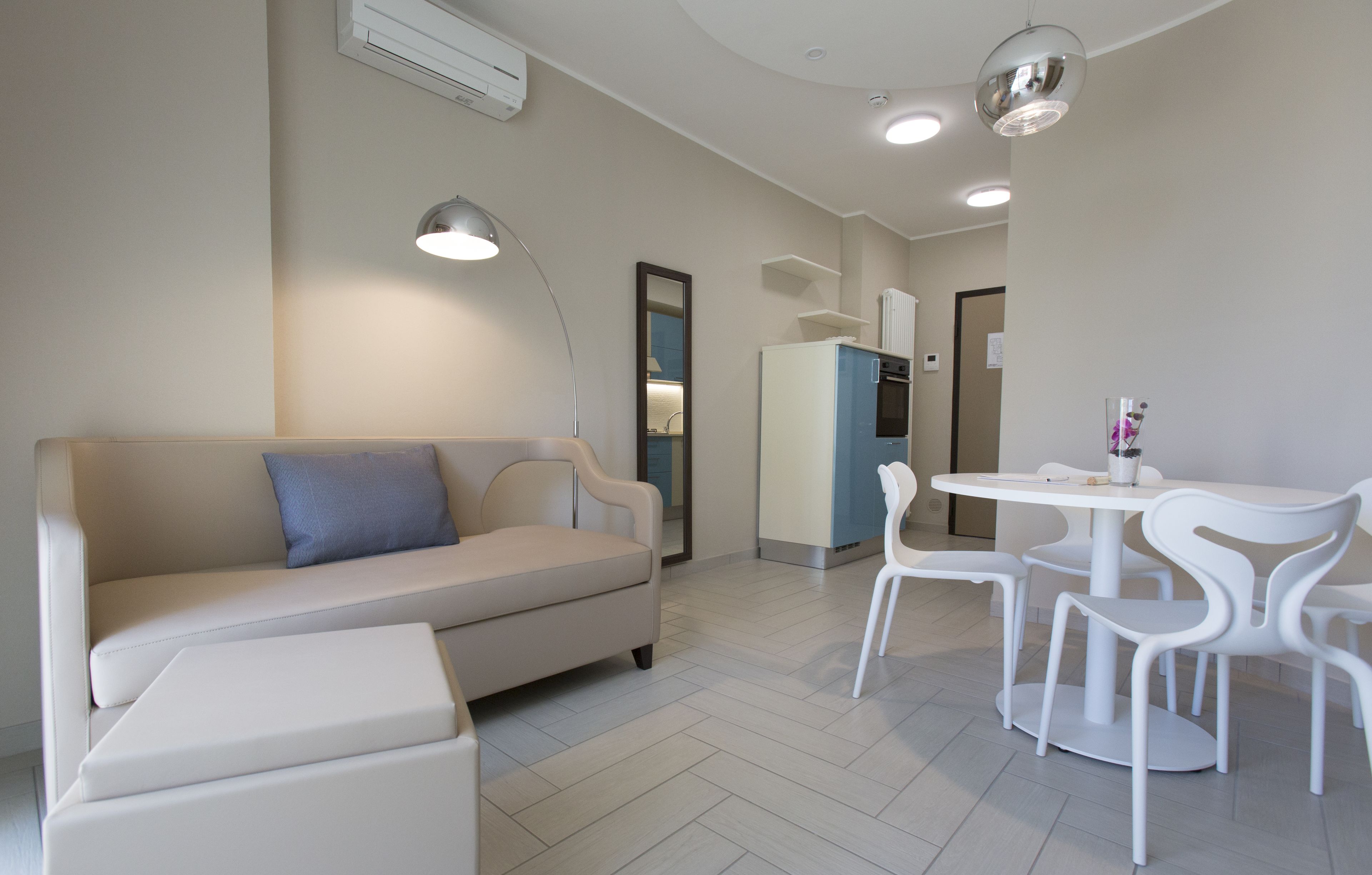Una sala de estar moderna con un sofá, una mesa de comedor con sillas y una cocina al fondo.