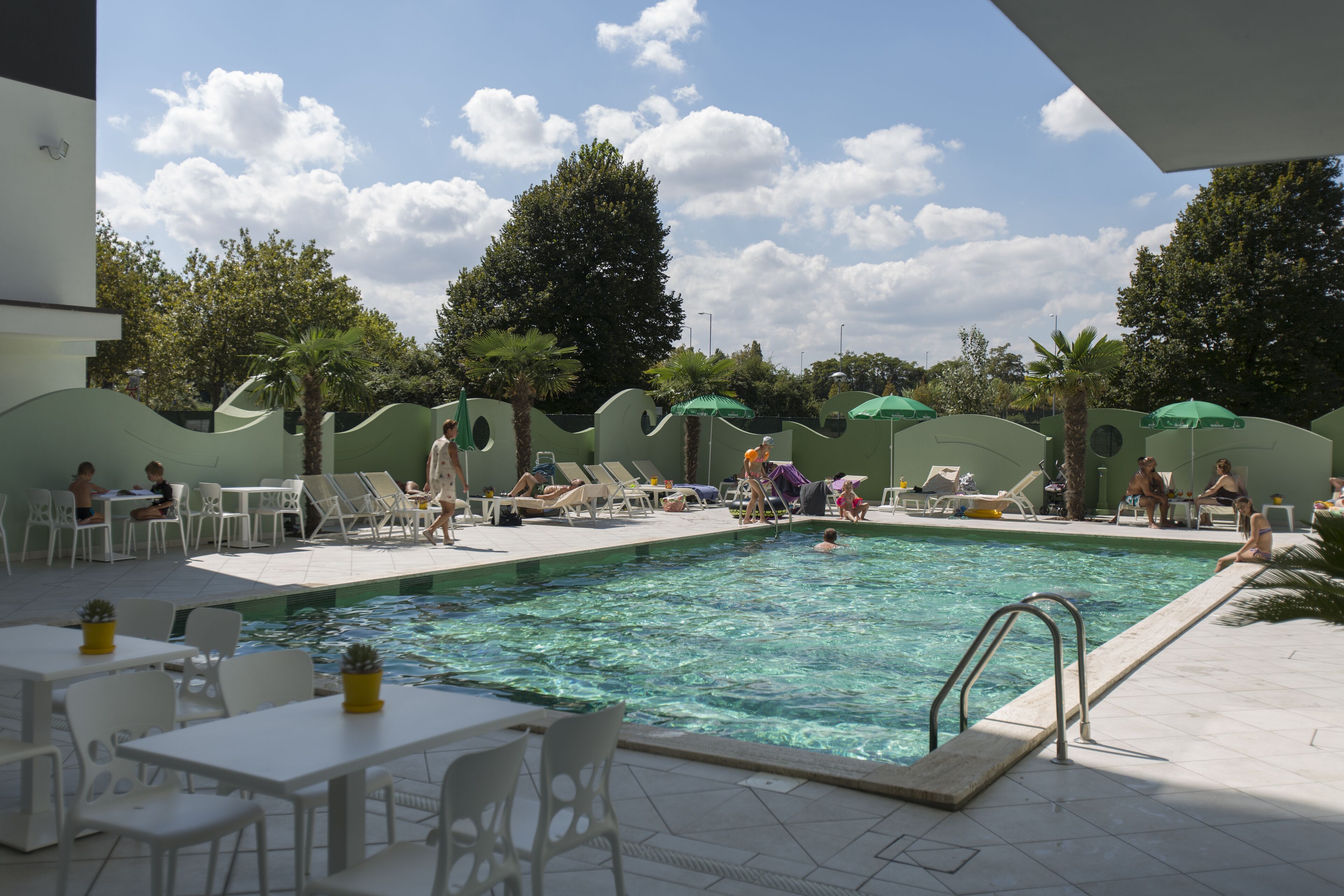 Un espace piscine aménagé avec des chaises longues, des parasols et des tables.