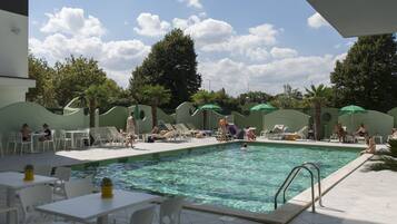 Un espace piscine aménagé avec des chaises longues, des parasols et des tables.