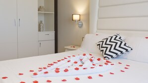 Una habitación de hotel con una cama bien hecha, una mesita de noche, una lámpara de pared y un armario.