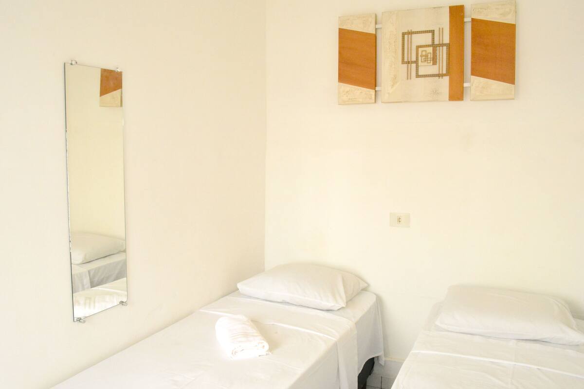 Ein Zimmer mit zwei Einzelbetten, einem großen Spiegel und einem Wandbild.