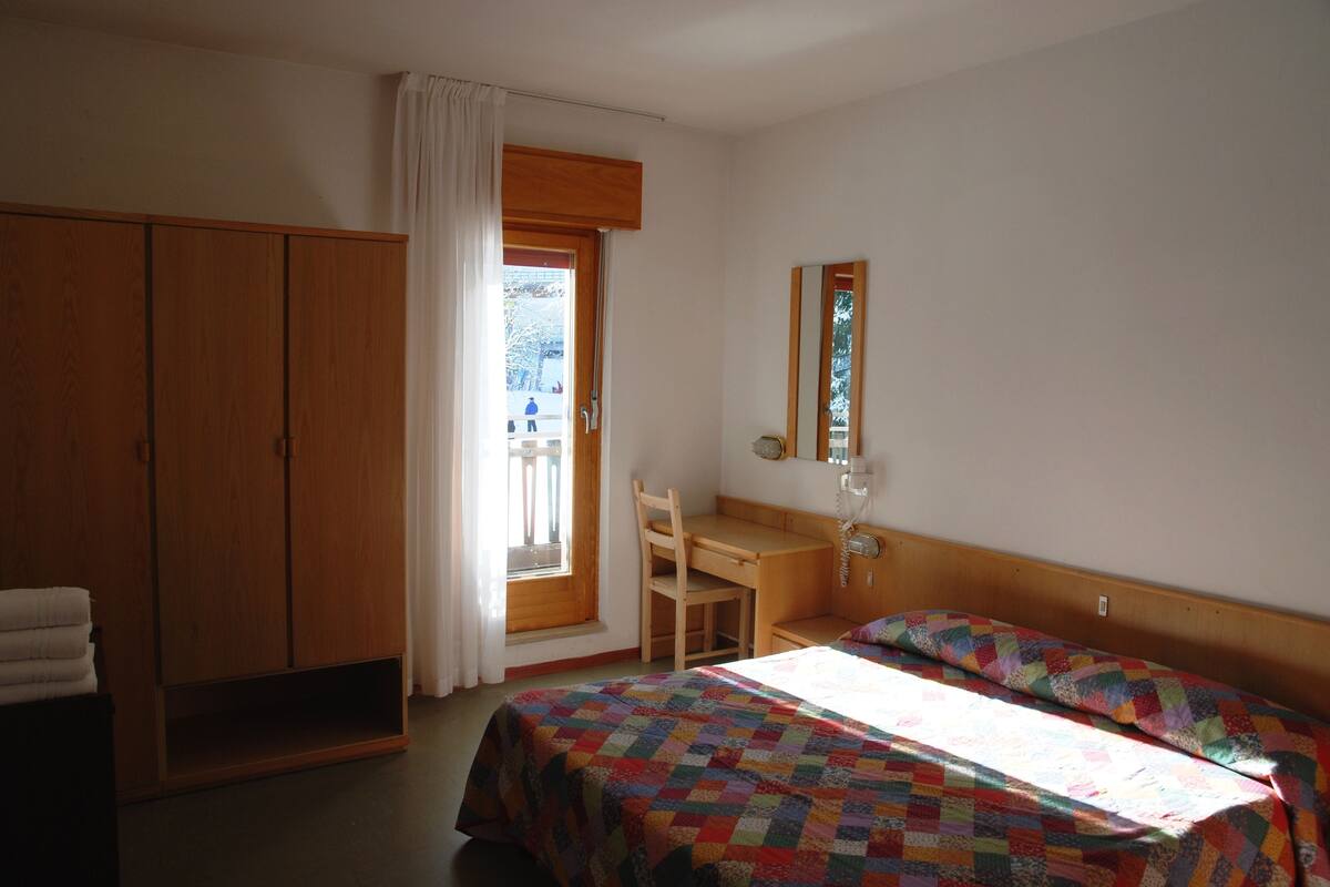 A bedroom with a bed, a desk, and a wardrobe.