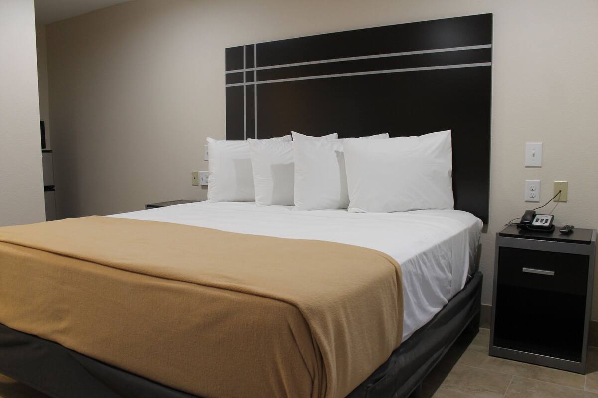 A hotel room with a bed, a bedside table, and a nightstand.