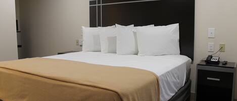 Una habitación de hotel con una cama, una mesita de noche y un buró.