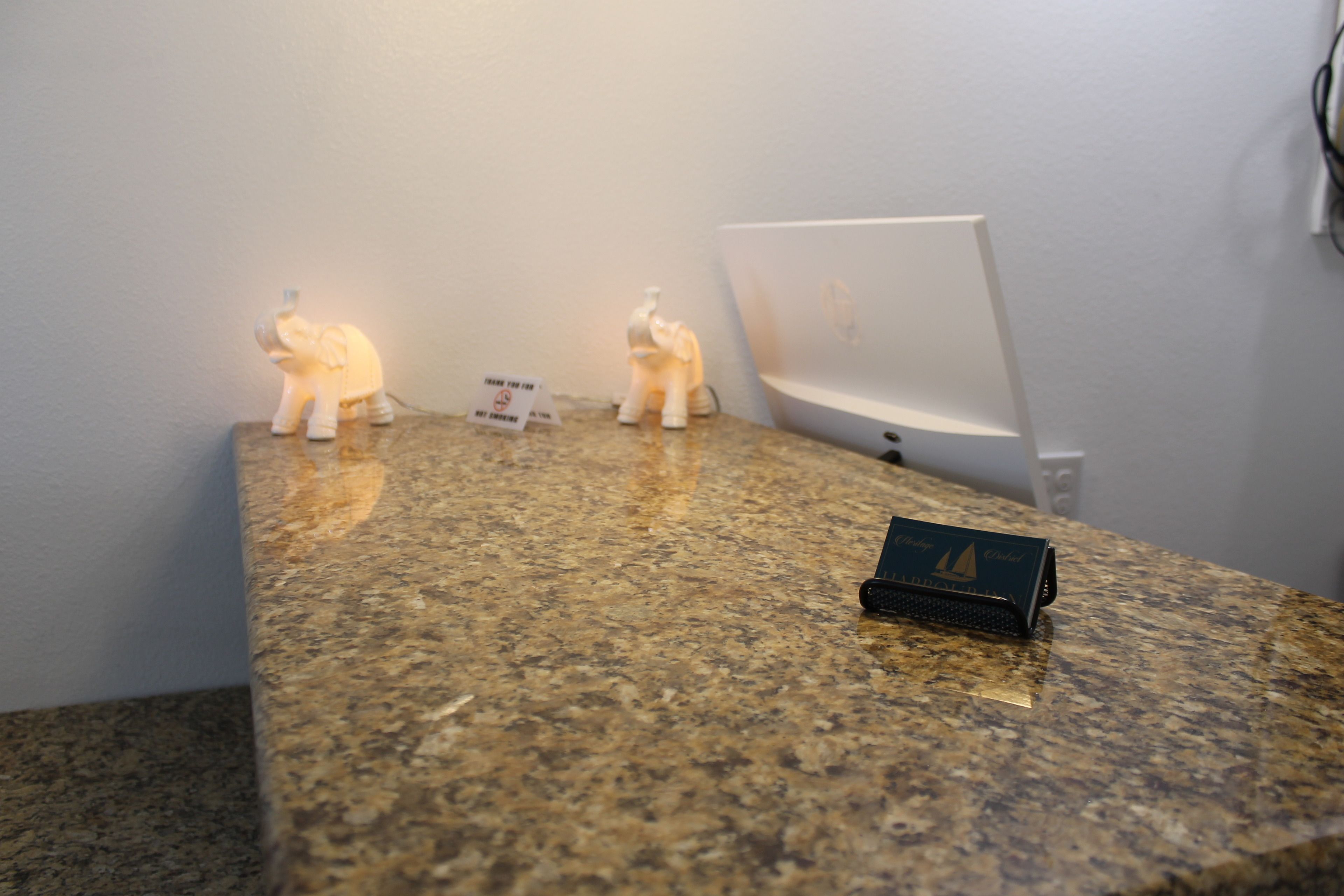A granite countertop with two illuminated elephant figurines, a sign, and a laptop.