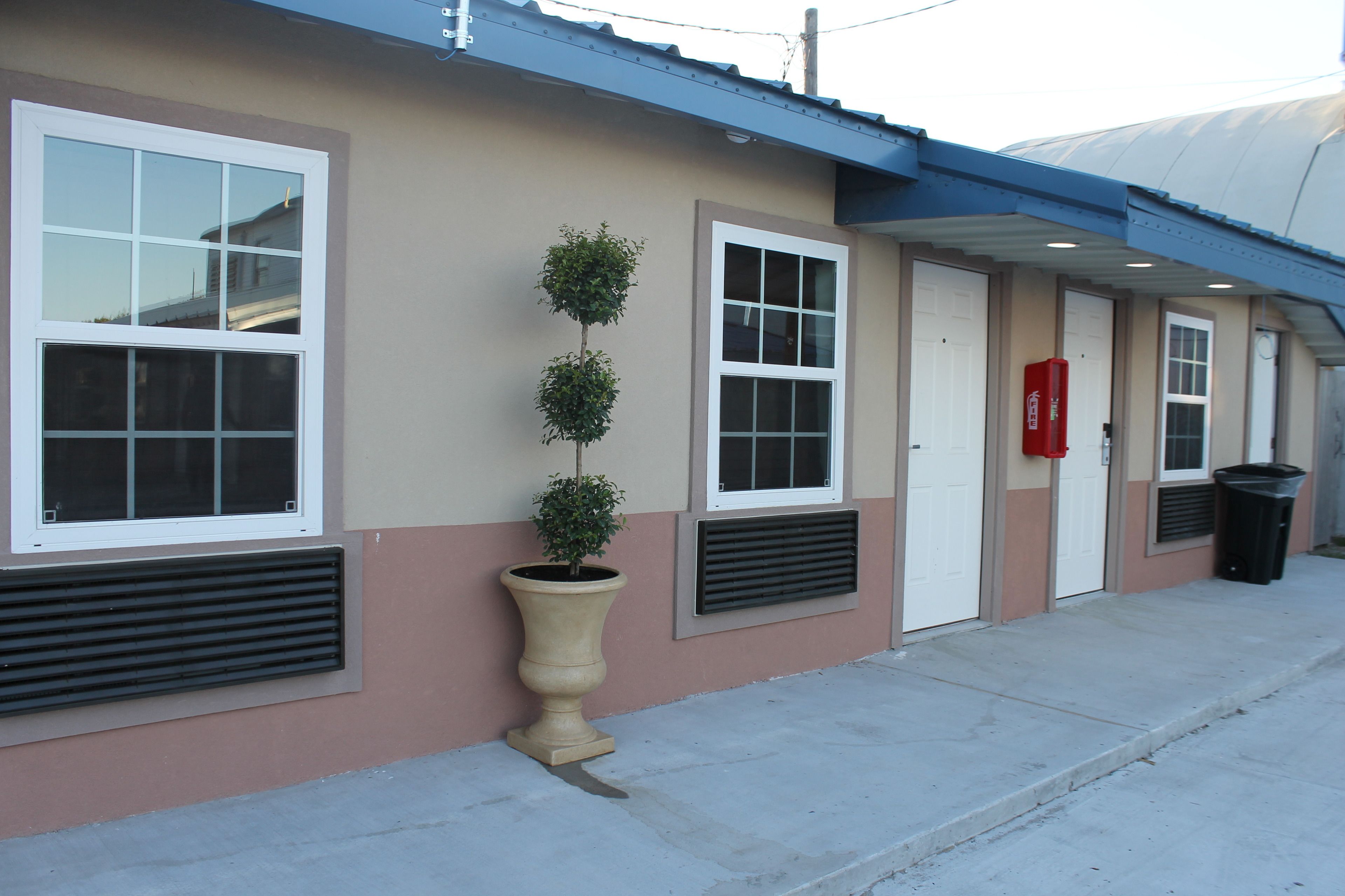 A building with large windows, a planter with a small tree, and a red mailbox.