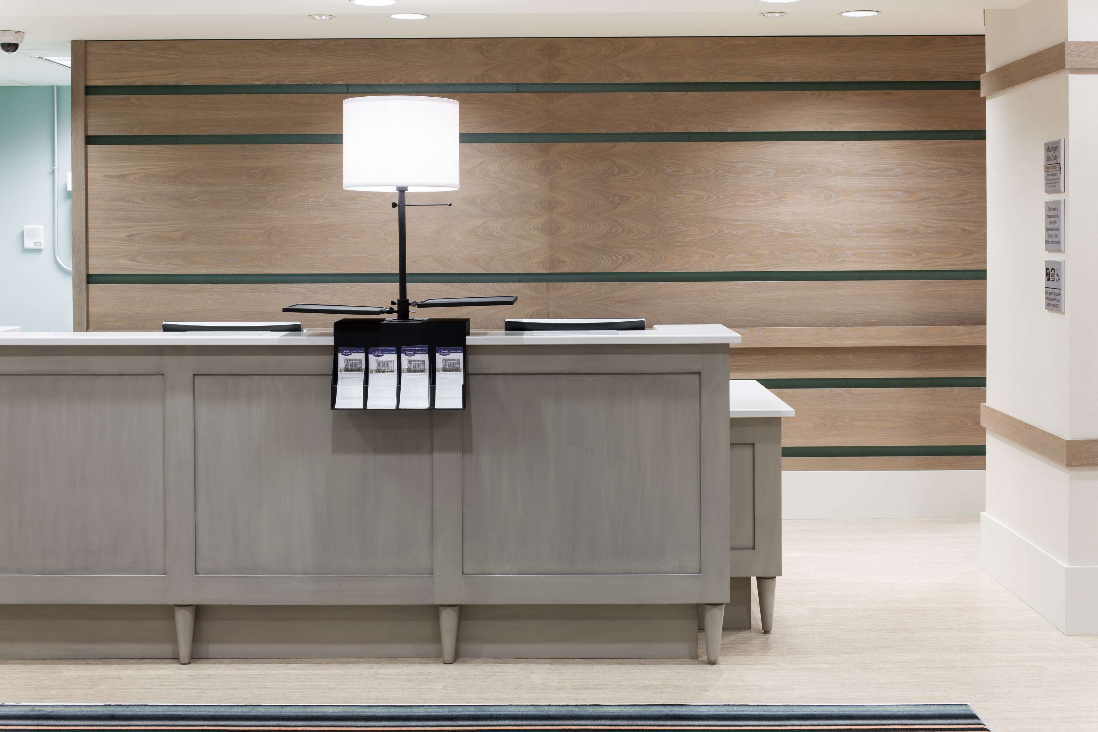 Un mostrador de recepción de diseño moderno, con un panel de pared de madera clara y una encimera blanca.