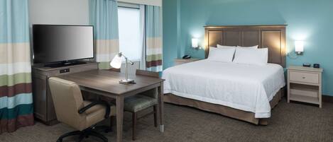 A hotel room with a bed, desk, chair, TV, and bedside lamps.