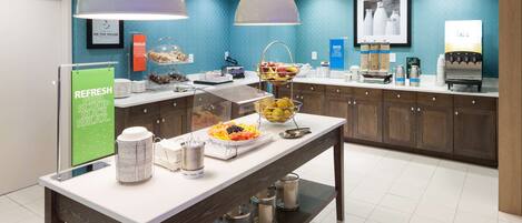 A buffet area with a variety of food items, a coffee station, and a sign promoting a skin care product.