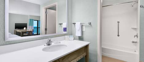 A modern bathroom with a large mirror, white sink, and a walk-in shower.